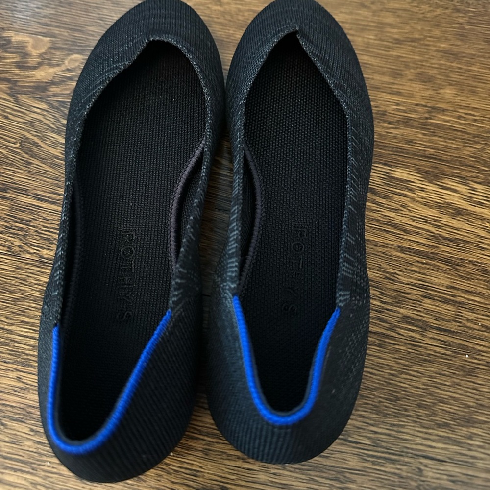 Brand new in box Rothy’s size 9 black ballet flat with blue accent detail.